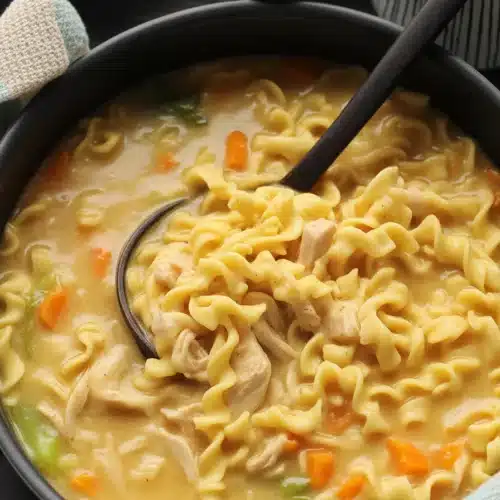 Creamy chicken noodle soup with chicken, egg noodles, and mixed vegetables in a bowl.