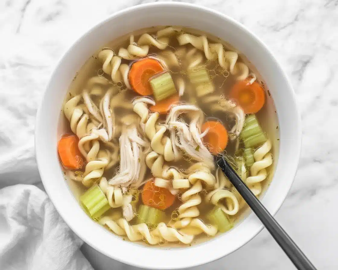 Bowl of homemade Chicken Noodle Soup made in a Crock Pot with vegetables and chicken.